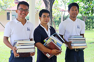 JPA Image Gallery - Three high school students with a pile of books - Jay Pritzker Academy, Siem Reap, Cambodia
