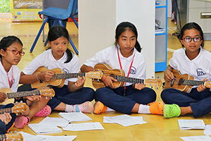 JPA Image Gallery - Middle school students sit in a circle on the floor with their ukuleles - Jay Pritzker Academy, Siem Reap, Cambodia