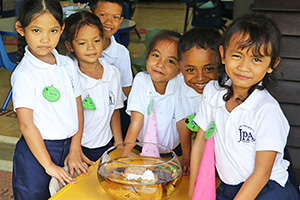 JPA Image Gallery - Primary students observe a fish bowl - Jay Pritzker Academy, Siem Reap, Cambodia