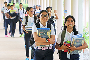 JPA Image Gallery - A group of students clutch their science books as they make their way down the outdoor corridor - Jay Pritzker Academy, Siem Reap, Cambodia