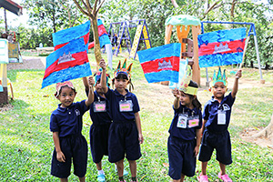 JPA Image Gallery - Kindergarten students display hand-made Cambodian flags in front of playground - Jay Pritzker Academy, Siem Reap, Cambodia