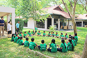 JPA Image Gallery - Primary students seated in circle on the grass playing duck-duck-goose - Jay Pritzker Academy, Siem Reap, Cambodia