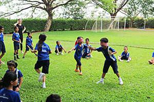 JPA Image Gallery - Primary students playing game with blindfolds on grass field for Khmer New Year celebration - Jay Pritzker Academy, Siem Reap, Cambodia