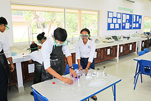JPA Image Gallery - High school students pouring liquid from flask during science experiment - Jay Pritzker Academy, Siem Reap, Cambodia