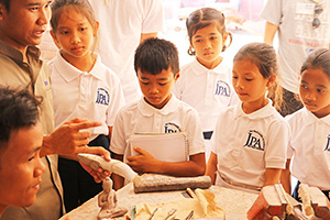 JPA Image Gallery - Students listen to presentation at field trip to stone carver workshop - Jay Pritzker Academy, Siem Reap, Cambodia
