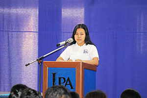 JPA Image Gallery - A female high school student speaks at the podium during assembly - Jay Pritzker Academy, Siem Reap, Cambodia