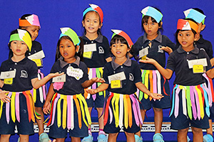 JPA Image Gallery - Kindergarten students sing while dressed up in paper pencils at assembly - Jay Pritzker Academy, Siem Reap, Cambodia