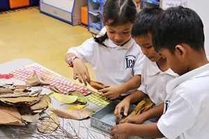 JPA Image Gallery - Primary students examine leaves and other specimens from nature for science class - Jay Pritzker Academy, Siem Reap, Cambodia