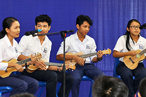 JPA Image Gallery - High school students strum ukuleles at a musical performance for an assembly - Jay Pritzker Academy, Siem Reap, Cambodia