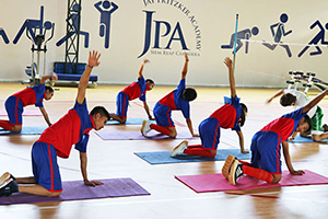JPA Image Gallery - High school students do stretches on yoga mats in the gym - Jay Pritzker Academy, Siem Reap, Cambodia