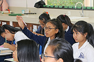 JPA Image Gallery - A student raises her hand to ask a question during class - Jay Pritzker Academy, Siem Reap, Cambodia