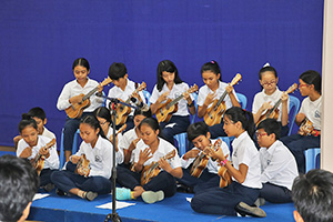 JPA Image Gallery - Students playing ukuleles at assembly musical performance - Jay Pritzker Academy, Siem Reap, Cambodia