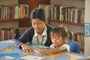 JPA Image Gallery - An older student reads to a younger student - Jay Pritzker Academy, Siem Reap, Cambodia