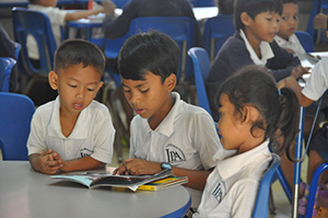 JPA Image Gallery - An older student reads to younger students in the library - Jay Pritzker Academy, Siem Reap, Cambodia