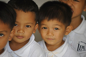 JPA Image Gallery - Primary students look at the camera as they queue - Jay Pritzker Academy, Siem Reap, Cambodia
