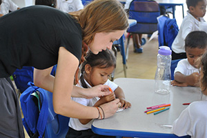 JPA Image Gallery - A teacher assists a young student with her pencil grip - Jay Pritzker Academy, Siem Reap, Cambodia