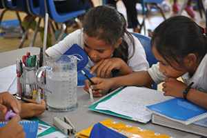 JPA Image Gallery - Primary students examine liquid in a jar - Jay Pritzker Academy, Siem Reap, Cambodia
