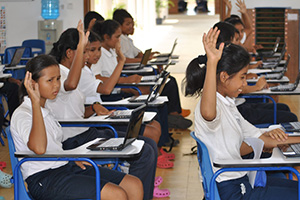 JPA Image Gallery - Students raise their hands in response to a question while sitting with their laptops - Jay Pritzker Academy, Siem Reap, Cambodia