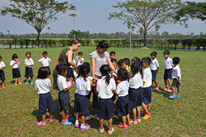JPA Image Gallery - Primary students gather around the teacher to collect water balloons - Jay Pritzker Academy, Siem Reap, Cambodia